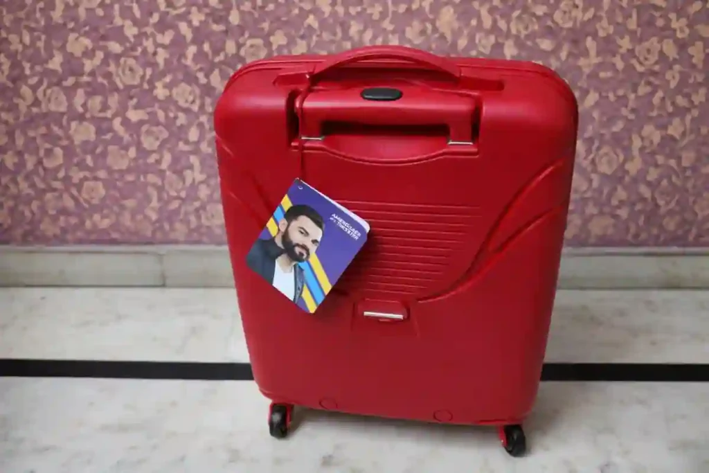 American Tourister red hard-shell trolley suitcase with integrated top handle and spinner wheels