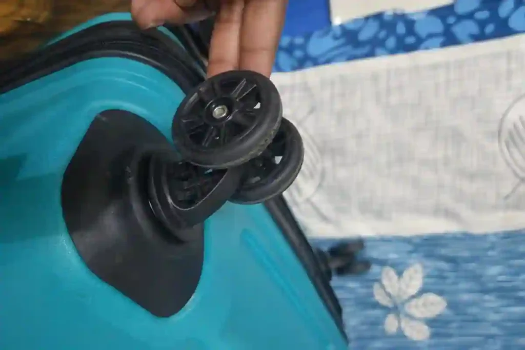 Close-up of a double spinner wheel on a blue hard-shell trolley bag, showing smooth-rolling wheels designed for easy movement and stability during travel